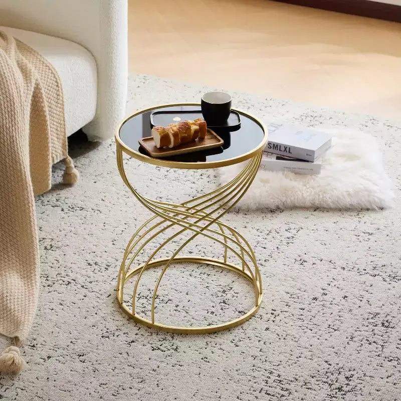 Table d’appoint élégante et moderne en forme de sablier, avec plateau en verre noir et piètement en métal doré